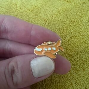 Gold enamel pin with a cute little airplane design